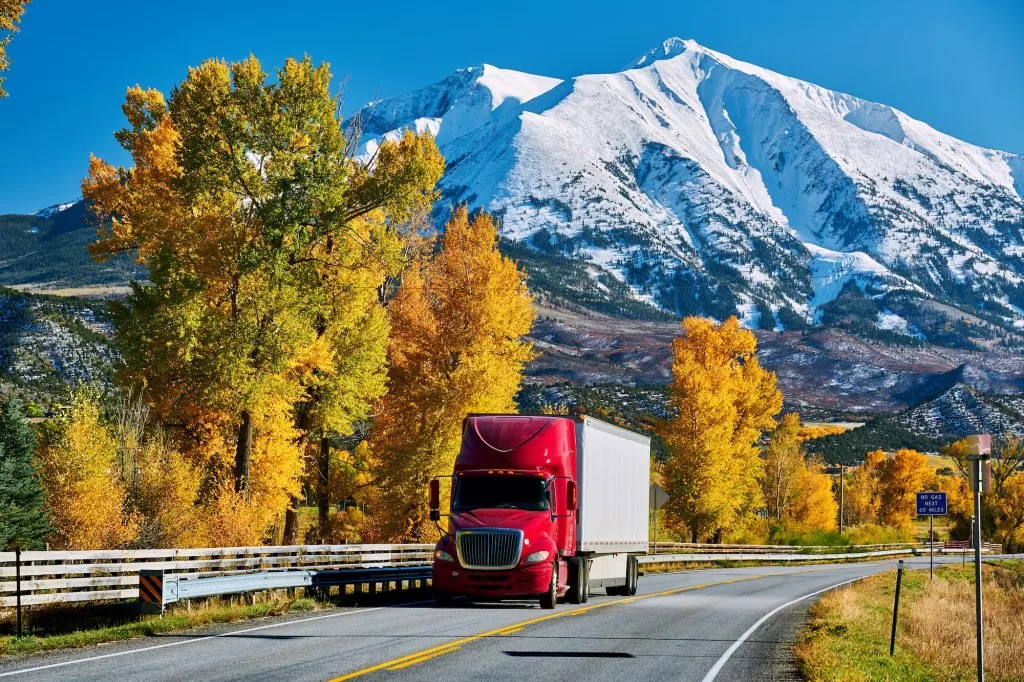 Red truck on highway in Colorado at autumn, USA. Mount Sopris landscape.